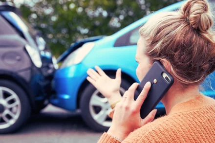 Distressed woman using her phone after a car accident.