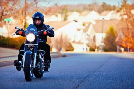 A man wearing a black jacket on his motorcycle.