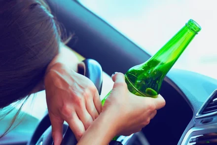 Drunk woman driver holding a bottle of beer.