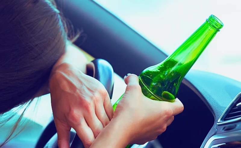 Drunk woman driver holding a bottle of beer.