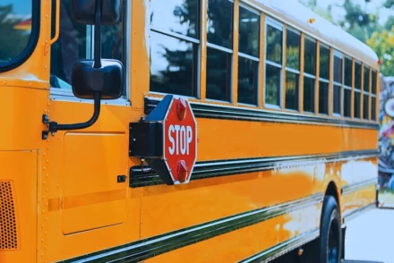 A yellow school bus with a stop signage in the side.