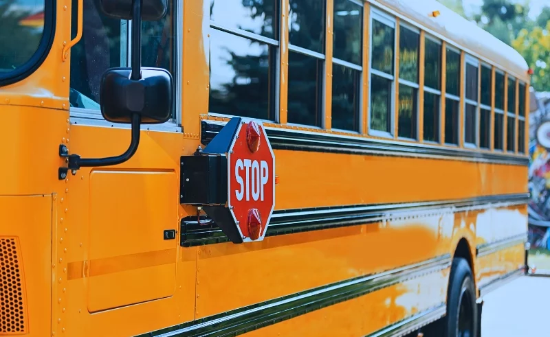 A yellow school bus with a stop signage in the side.