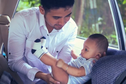 Father carrying a baby to a child seat.