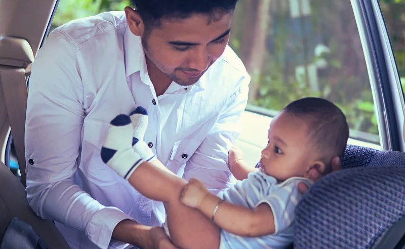Father carrying a baby to a child seat.